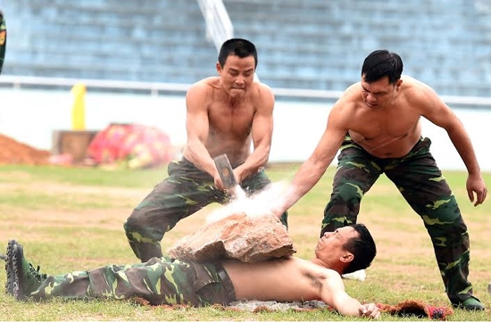 Lưng trần nằm lên thuỷ tinh, ngực làm bàn kê để đập vỡ tảng đá lớn.