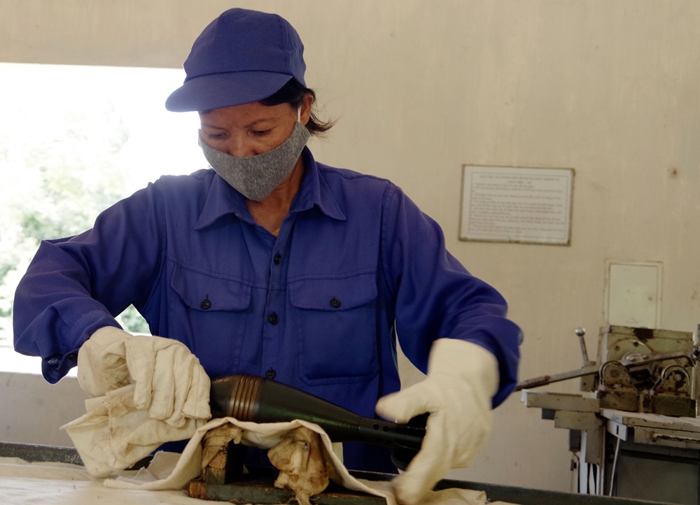 Họ dùng giấy ráp, bàn chải sắt để đánh bật sơn và gỉ sắt trên bề mặt ngoài của quả đạn cối 60.