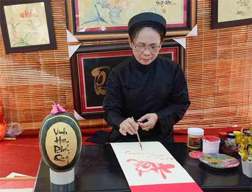 “Bà đồ” viết chữ tặng khách tham quan hội hoa xuân.