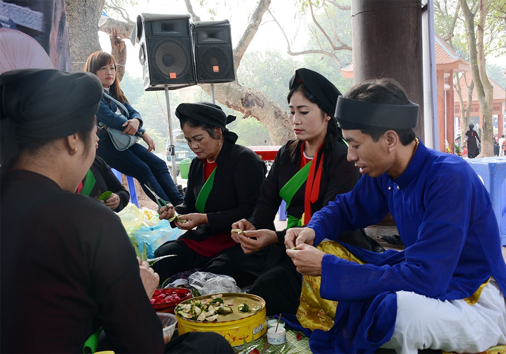 Ở phía sau, các liền anh, liền chị têm trầu cánh phượng mời du khách.