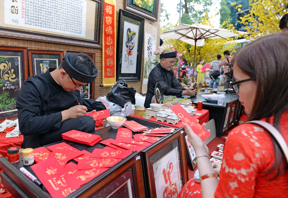 Những niềm mong ước và lời chúc tốt đẹp được thể hiện bằng chữ thư pháp trên bao lì xì đỏ.