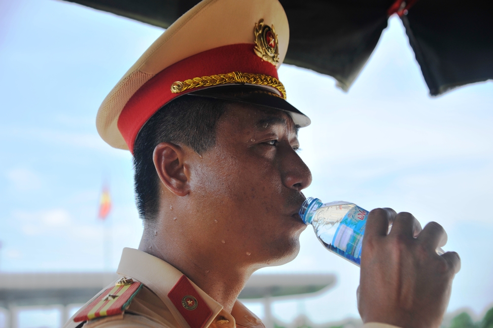 Ngoài trời quá nắng nóng khiến gương mặt các đồng chí CSGT không lúc nào ngớt mồ hôi và liên tục phải uống nước.