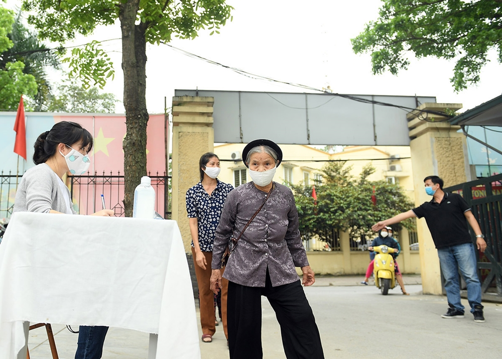 Người dân nghèo đến nhận gạo được hướng dẫn xếp hàng giãn cách từ ngoài cổng, và rửa tay sát khuẩn tại bàn đón tiếp và nhắc nhở đeo khẩu trang đúng cách.