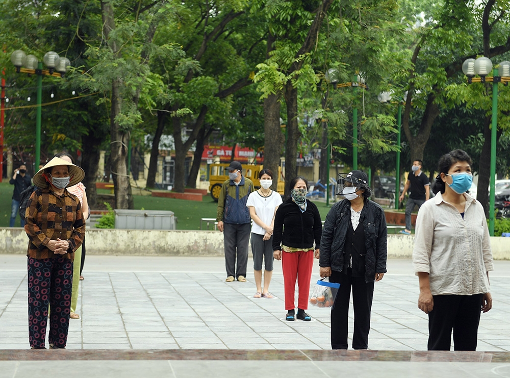 Trong sân người dân được hướng dẫn đứng xa nhau 2m và lần lượt lên máy nhận gạo theo thứ tự.