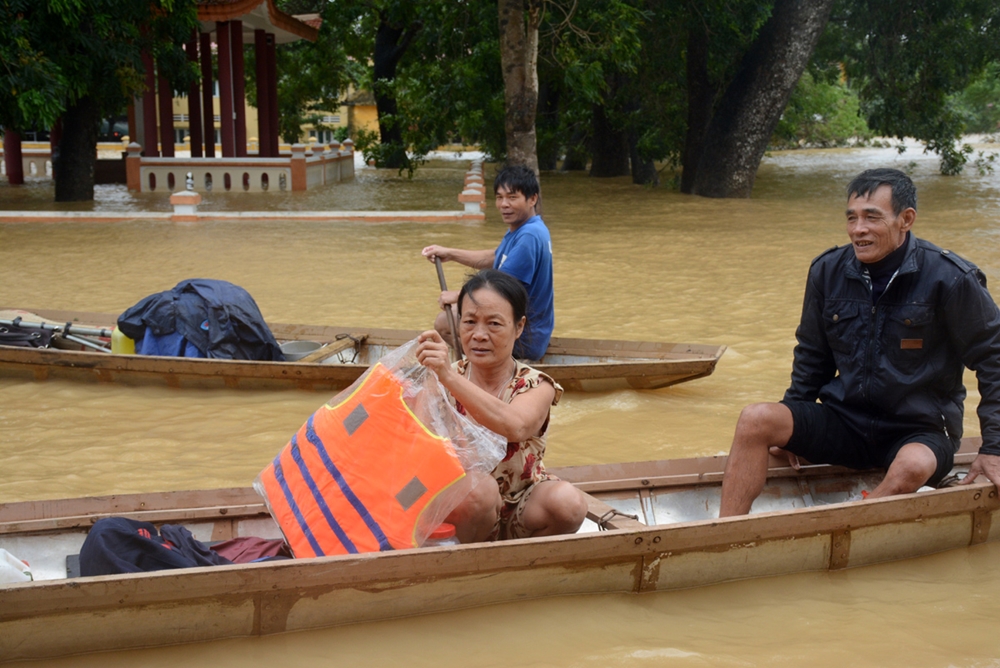 Người dân chèo thuyền đi nhận áo phao và hàng cứu trợ.