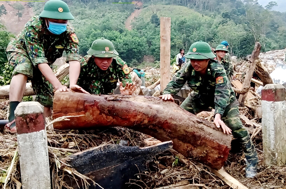 Lực lượng cứu hộ phải cắt khúc những gốc cây to mới vận chuyển về vị trí tập kết để tìm kiếm nạn nhân.