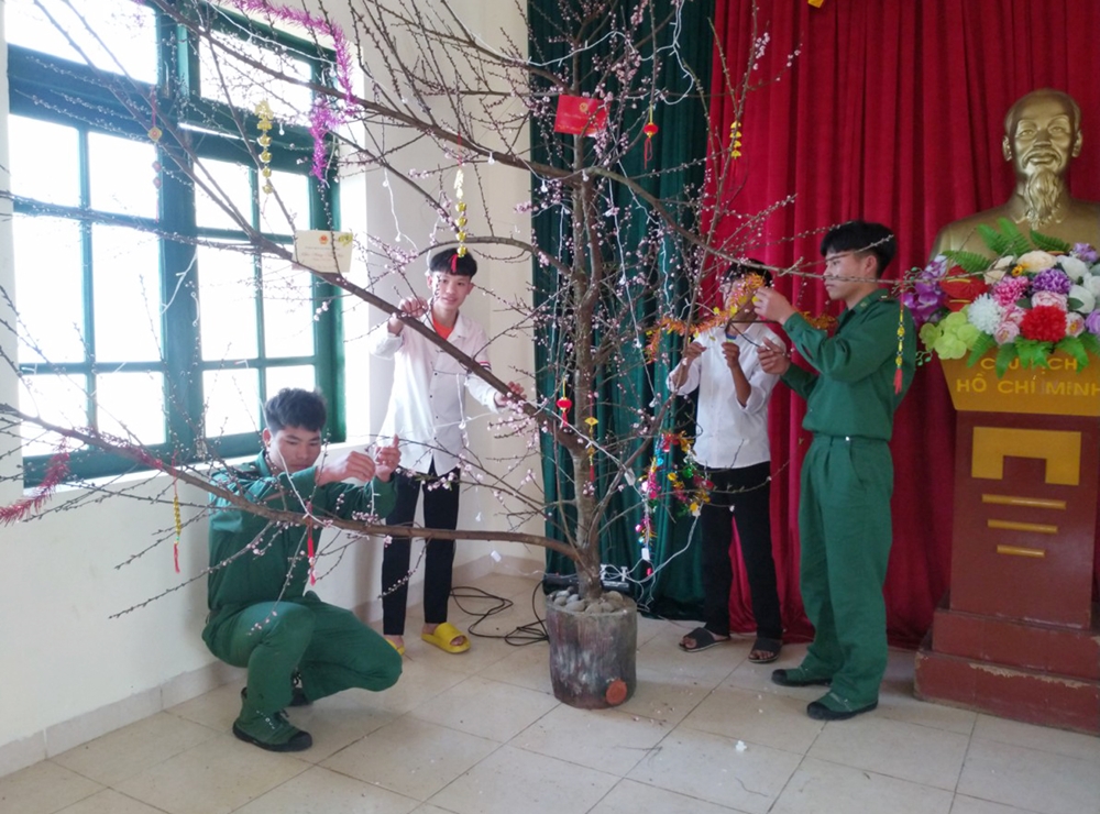 Các con nuôi cùng các chiến sĩ Đồn BP Sin Suối Hồ, BĐBP Lai Châu trang trí cành đào đón Xuân. Ảnh: Đức Long