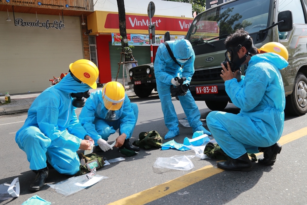 Bộ đội phòng hóa khẩn trương mang đeo trang bị bảo hộ để phun khử khuẩn.