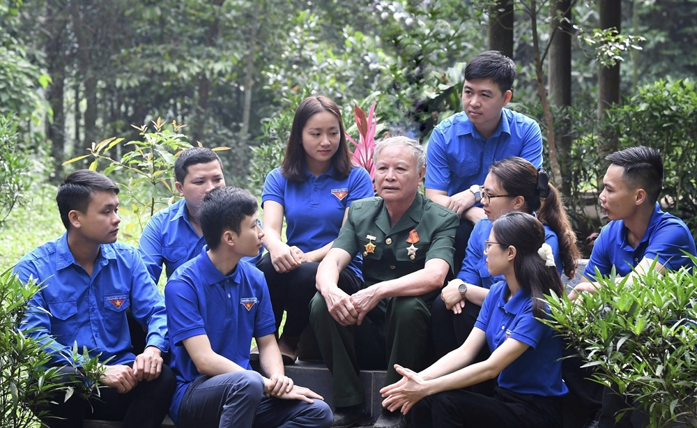 Đảng viên, cựu chiến binh Bùi Bình Bài đang kể chuyện truyền thống và những câu chuyện, việc làm ý nghĩa của Chủ tịch Hồ Chí Minh cho các đoàn viên, thanh niên huyện Chợ Đồn nghe tại Khu di tích lịch sử Quốc gia đặc biệt Nà Pậu, xã Lương Bằng, nơi Bác Hồ từng sống và làm việc đầu năm 1951.