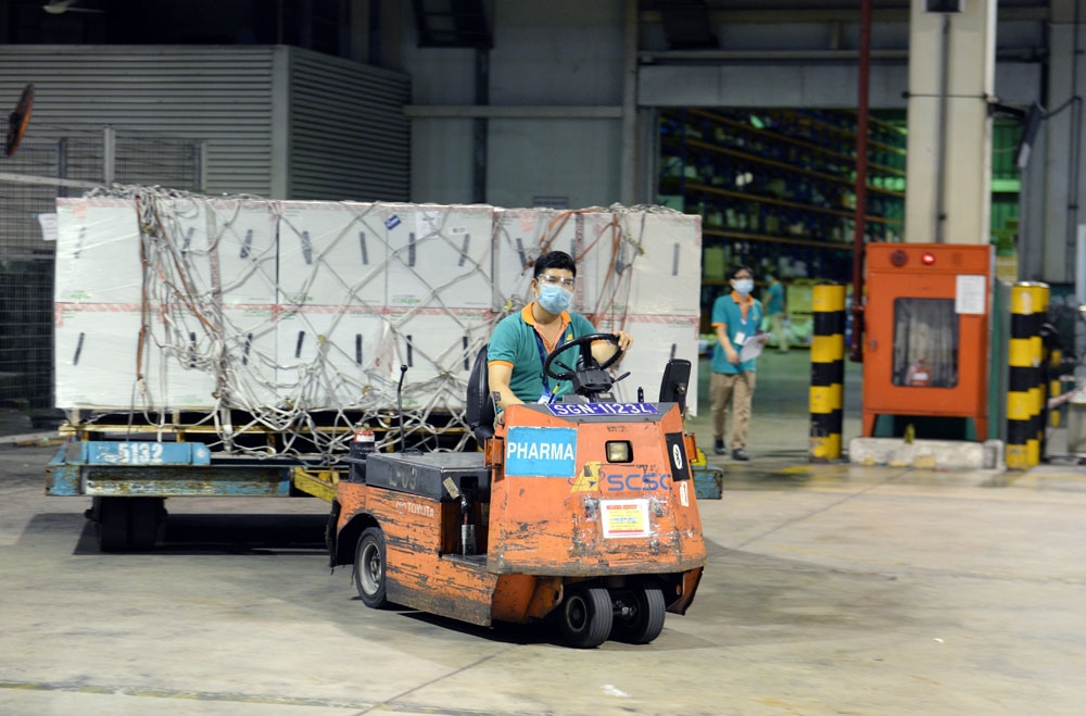 Chiếc xe rơ-moóc chuyên dụng cỡ nhỏ chở những kiện vaccine Moderna đầu tiên ra sảnh giao hàng của sân bay.