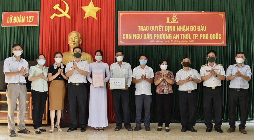 Lãnh đạo Lữ đoàn 127 trao quyết định nhận đỡ đầu con ngư dân và trao quà tặng gia đình em Trần Ngọc Huyền.