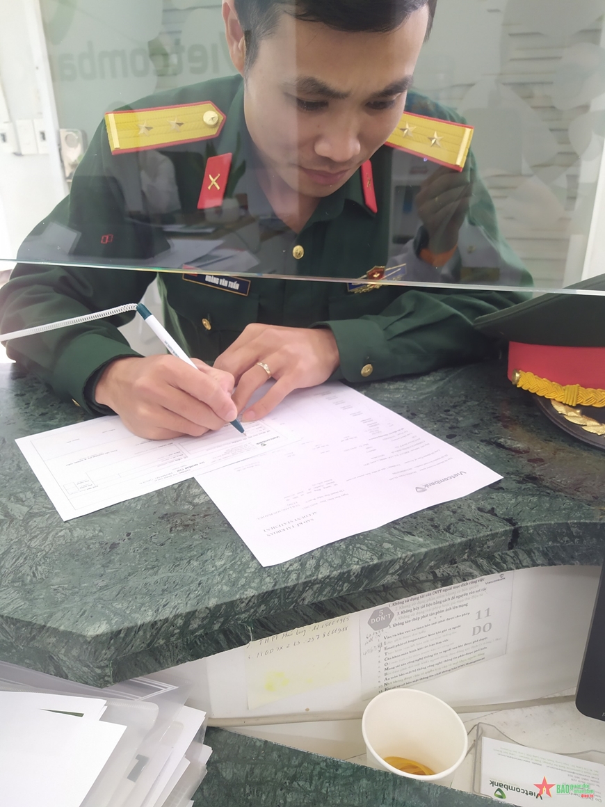 Trung úy Hoàng Văn Tuấn tại Phòng giao dịch Hữu Lũng viết giấy ủy nhiệm chi. 