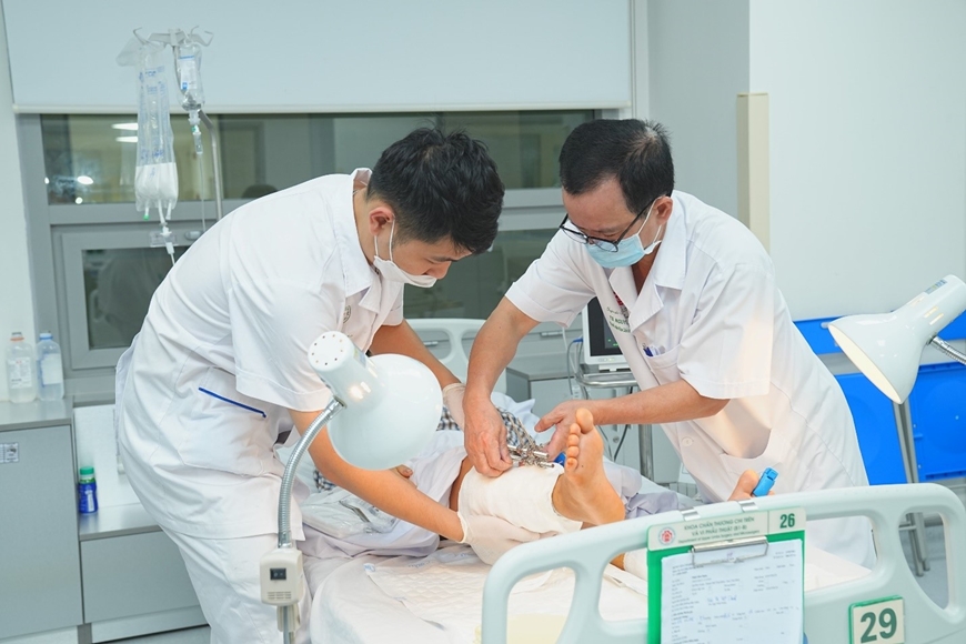 TS, BS Nguyễn Viết Ngọc, Khoa Chấn thương chi trên và Vi phẫu thuật thăm khám cho bệnh nhân sau phẫu thuật.