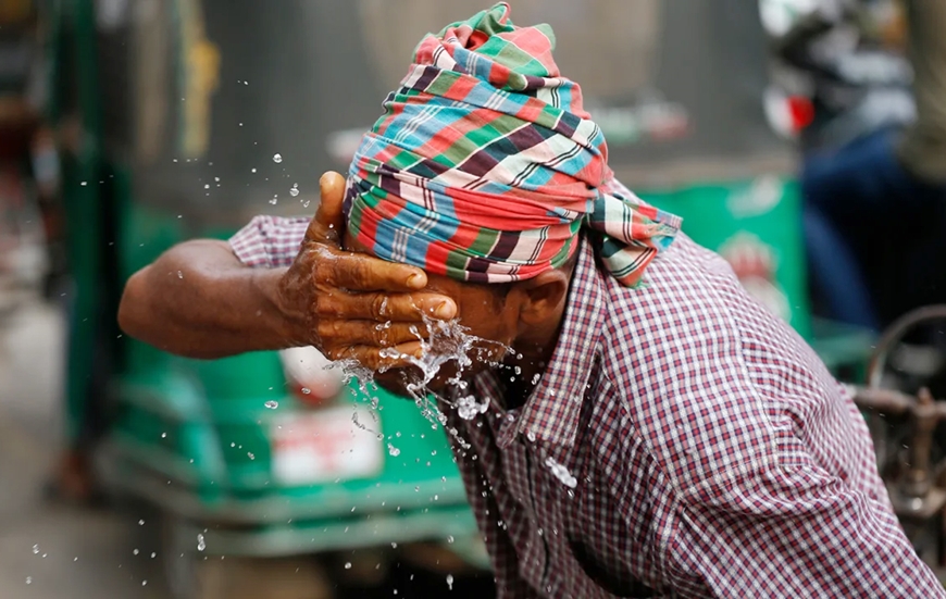 Một người kéo xe đang té nước lên mặt để giảm bớt nắng nóng ở thủ đô Dhaka, Bangladesh vào ngày 16-4. Ảnh: CNN