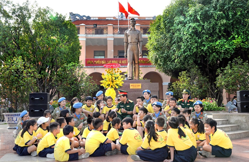 Học sinh nghe kể chuyện truyền thống dưới chân tượng đài Nguyễn Tất Thành. 