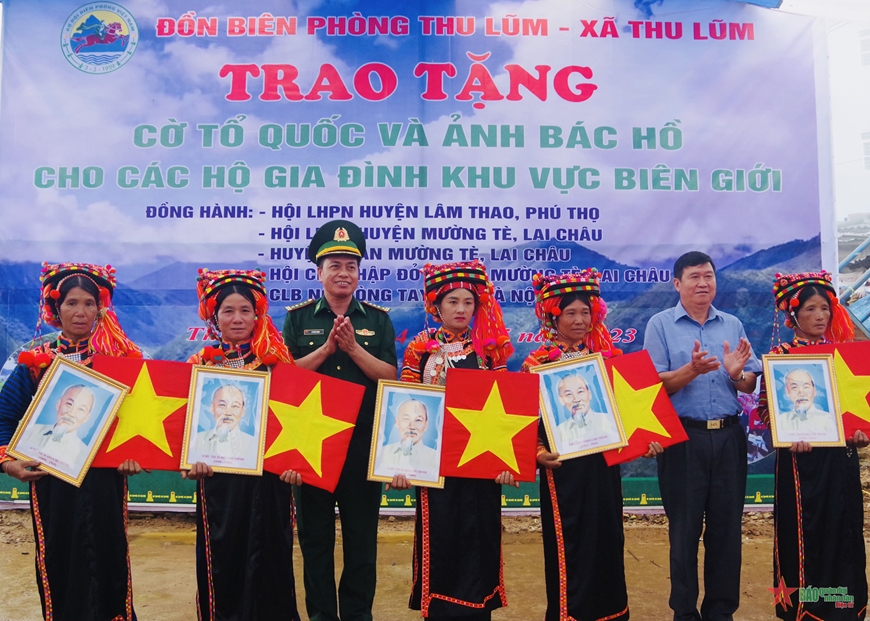 Đại diện Bộ chỉ huy Bộ đội Biên phòng tỉnh Lai Châu và huyện Mường Tè trao cờ Tổ quốc và ảnh Bác Hồ tặng người dân. 