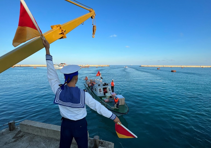 Chiến sĩ hoa tiêu đảo Đá Tây A phất cờ hiệu báo luồng an toàn cho xuồng ra vào đảo. 