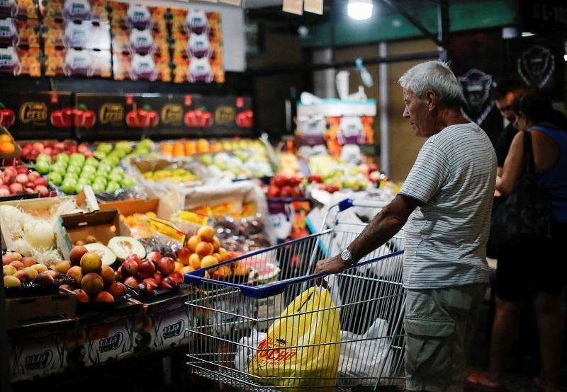  Khách hàng đứng trước quầy bán hoa quả trong một siêu thị ở Buenos Aires, Argentina. Ảnh: Reuters