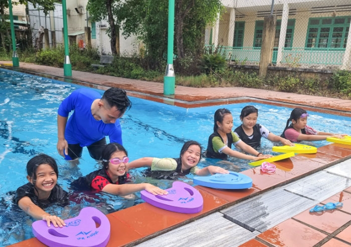 Giáo viên thuộc Tổ chức Swim Vietnam dạy bơi cho trẻ em tại bể bơi Trường Tiểu học Lương Thế Vinh, phường Tân An (Hội An, Quảng Nam). Ảnh: NHƯ CẨM 