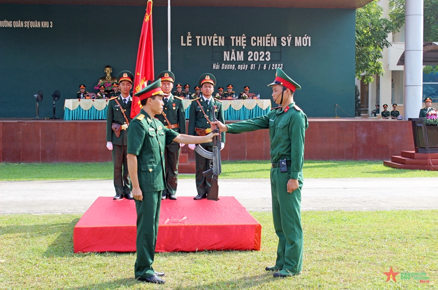 Lãnh đạo Trường Quân sự Quân khu 3 thực hiện nghi lễ trao súng cho chiến sĩ mới. 