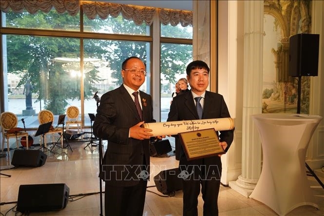 Ông Đỗ Xuân Hoàng, Chủ tịch Hội người Việt Nam tại LB Nga, trao cho ông Hoàng Anh Tuấn, Cục trưởng Cục Lưu trữ Văn phòng Trung ương Đảng Cộng sản Việt Nam bản gốc tờ báo “Sự thật” ngày 27-1-1924, trong đó có bài viết của Chủ tịch Hồ Chí Minh. 