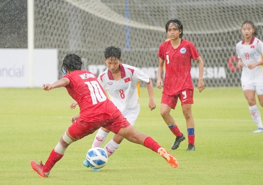 U19 nữ Việt Nam và U19 nữ Singapore thi đấu dưới trời mưa nặng hạt. Ảnh: VFF