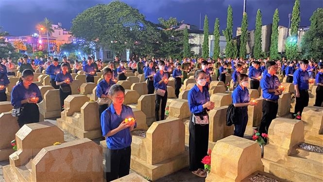 Đoàn viên thanh niên thắp nến tri ân tại các phần mộ liệt sĩ thuộc nghĩa trang liệt sĩ thành phố Quy Nhơn. Ảnh: TTXVN