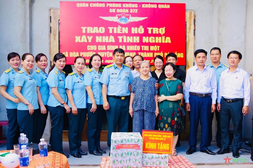 Các đại biểu chụp ảnh lưu niệm với gia đình bà Nhiêu Thị Một trong buổi trao tiền hỗ trợ xây nhà tình nghĩa. 