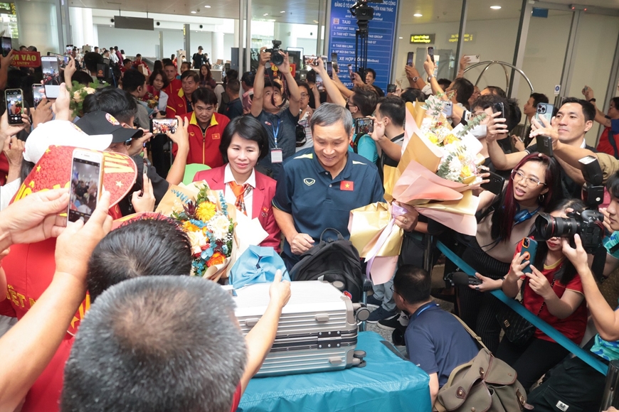 Thầy trò huấn luyện viên Mai Đức Chung được đông đảo phóng viên và người hâm mộ chào đón tại sân bay Nội Bài vào trưa 3-8. Ảnh: QUÝ LƯỢNG 
