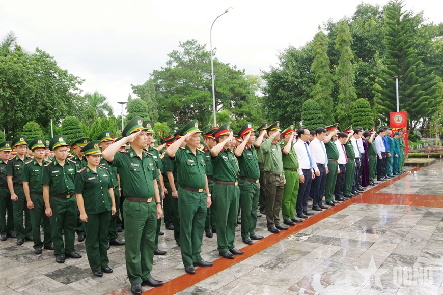 Photojournalism editorial photo of Vietnamese government officials and citizens laying wreaths at a war martyrs cemetery in Hanoi for Invalids and Martyrs Day — factual, respectful, no text overlay