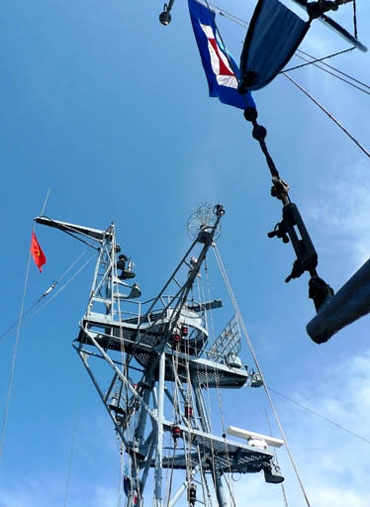 Lá cờ Tổ quốc tung bay trong gió trên cột cờ kỳ hạm HQ861 trước giờ xuất phát làm nhiệm vụ tuần tra liên hợp và diễn tập chống cướp biển