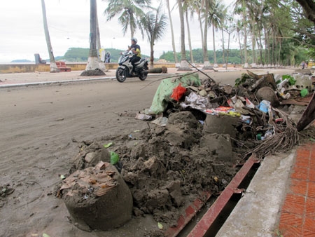 Mặc dù công ty vệ sinh môi trường đã thu dọn từ sáng, song trên bờ biển đường 295, phường Vạn Sơn (quận Đồ Sơn), đất cát vẫn ngổn ngang.