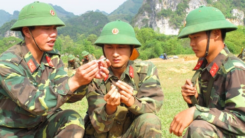 Cán bộ hướng dẫn động chiến sĩ thực hiện động tác tra dây cháy chậm vào kíp.