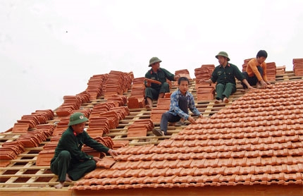 Cán bộ, nhân viên Đội xây dựng cơ sở số 6 (Ban CHQS Quế Phong) giúp dân dựng lại nhà ở khu tái định cư bản Huôi Su - Huôi Lạn, xã Tiền Phong, Quế Phong.