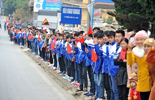 Người dân và các em học sinh đứng kín bên đường cổ vũ cho đoàn đua.