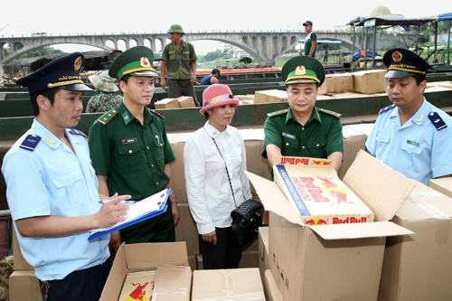 Kiểm soát viên Trạm kiểm soát Biên phòng Ka Long, thành phố Móng Cái và nhân viên hải quan kiểm tra lô hàng nước tăng lực Red bull xuất khẩu sang Trung Quốc.