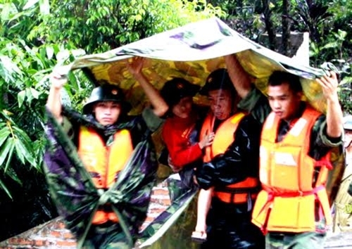Chiến sĩ Lữ đoàn 242 đang đưa một cháu nhỏ trong một ngôi nhà ở vùng nguy hiểm thuộc phường Mông Dương ra nơi an toàn, trước khi nước lũ dâng cao cô lập ngôi nhà.