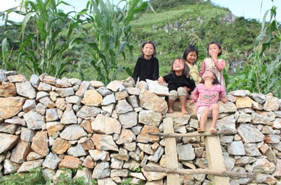 Nụ cười hồn nhiên trên bờ rào đá cạnh nhà của trẻ em người Mông