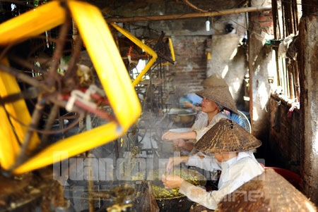 Người thợ khéo léo cho kén qua 1 lỗ nhỏ, kéo thành sợi và cuộn vào guồng