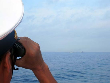 Một chiến sỹ trên tàu HQ 261 hướng ống nhòm về phía hai tàu Trung Quốc để quan sát, xác định vị trí của mục tiêu.