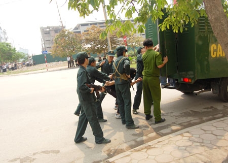 Áp giải đối tượng bắt cóc con tin lên xe.