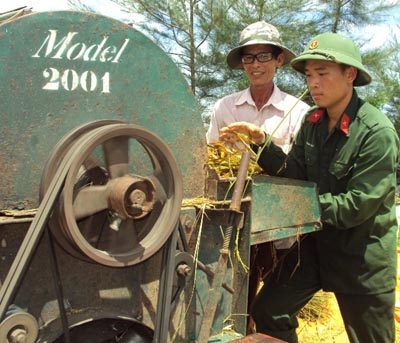 Binh nhất Võ Văn Việt đang giúp dân tuốt lúa.