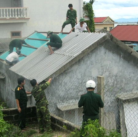 Cán bộ, chiến sỹ đang dọn dẹp những đống ngói vỡ ở dưới dất và trên tầng thượng của nhà dân bị tốc mái.