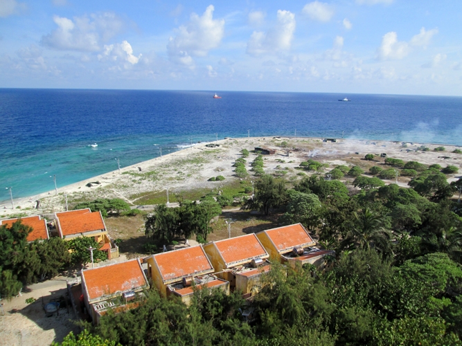 Những ngôi nhà mái đỏ của ngư dân nổi bật trong màu xanh của cây và nước biển.