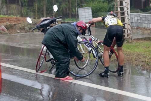 Một vận động viên phải thay lốp trong cơn mưa.