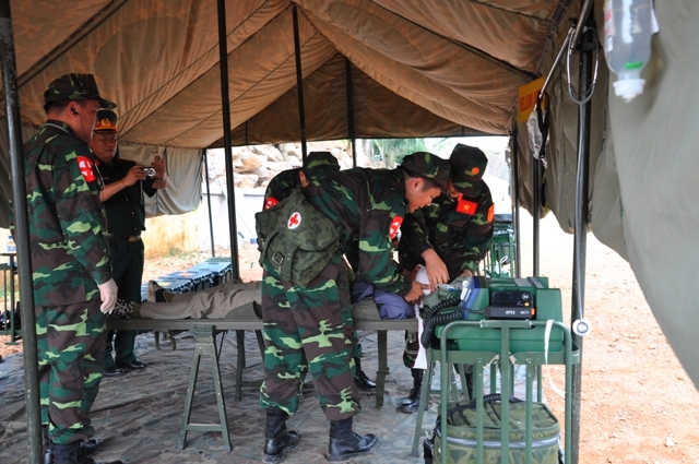 Trong khu lều dã chiến, các bác sĩ quân y tiến hành khám, chữa cho người bị thương